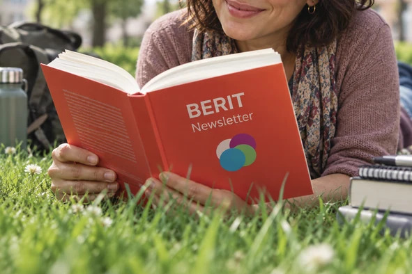 Eine Frau liest in einem Buch mit dem Titel "BERIT Newsletter"